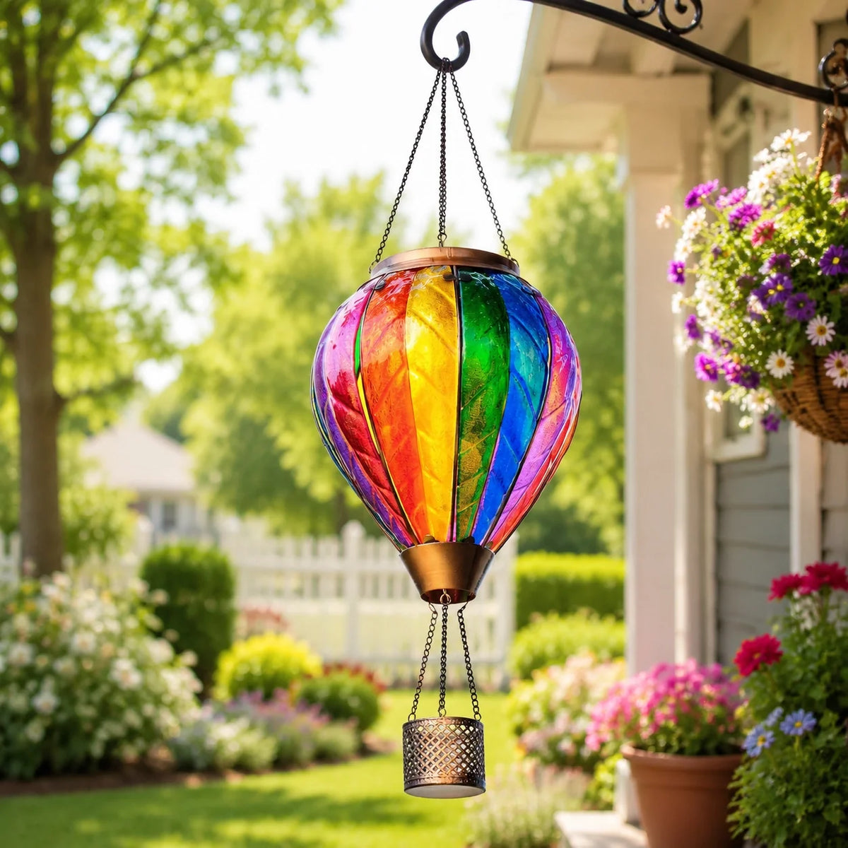 Classic rainbow hot air balloon solar lantern hanging beside a colorful flower garden